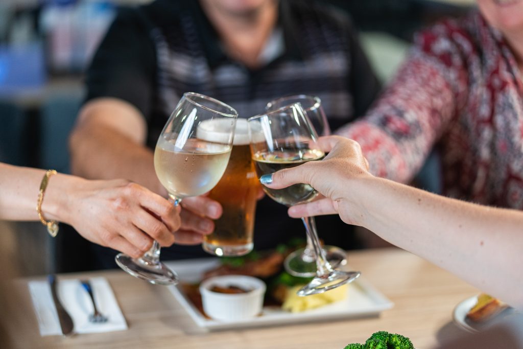 Four people clinking glasses over their dinner